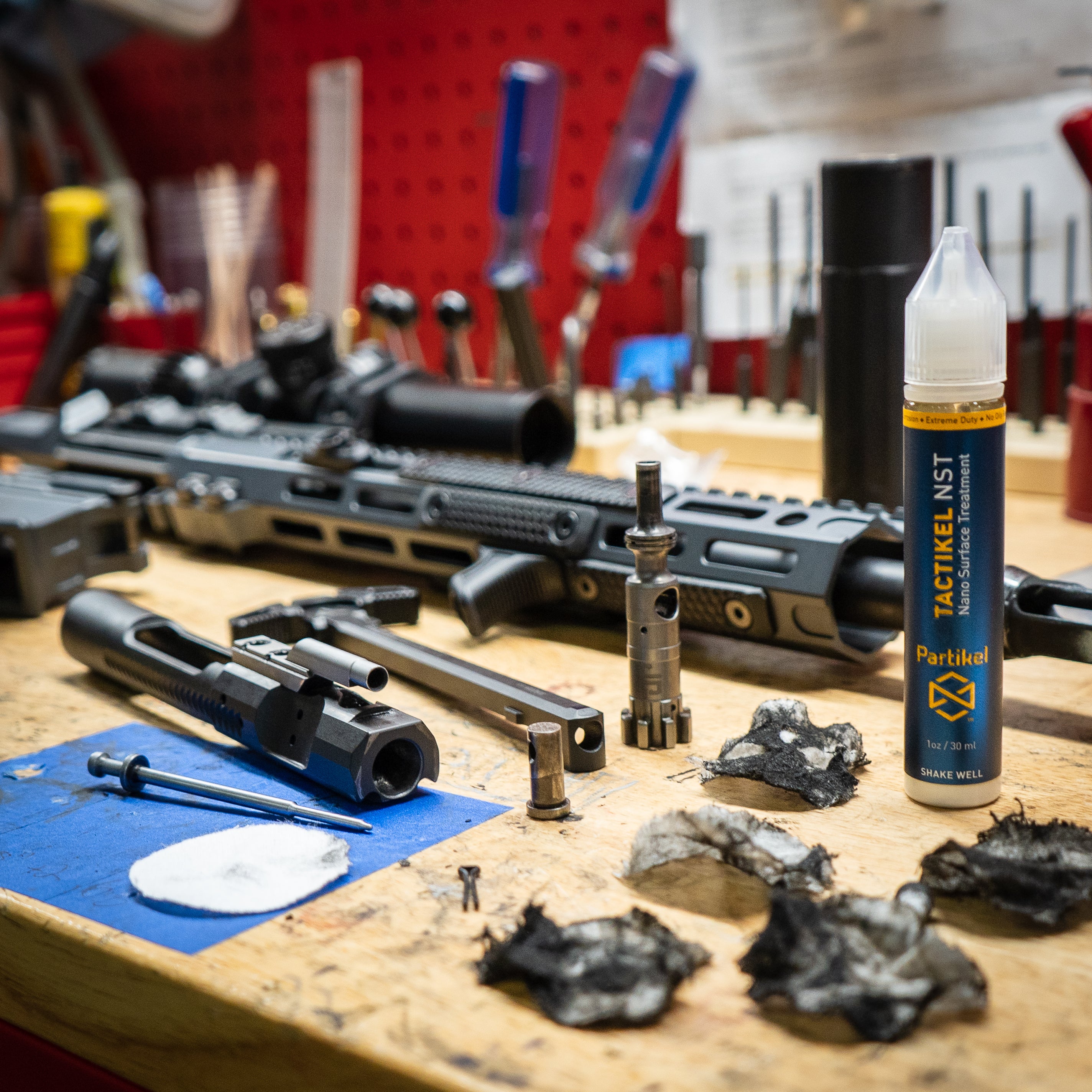 Gunsmith's workbench with disassembled TX-15 rifle. Shows Bolt Carrier Group after cleaning. A bottle of Tactikel NST is in the foreground.
