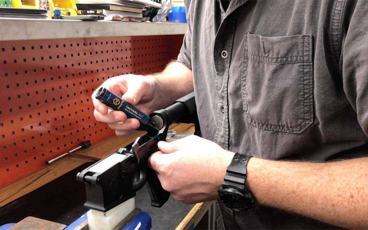 Gunsmith applying Tactikel NST lubricant to an AR-15 receiver. 
