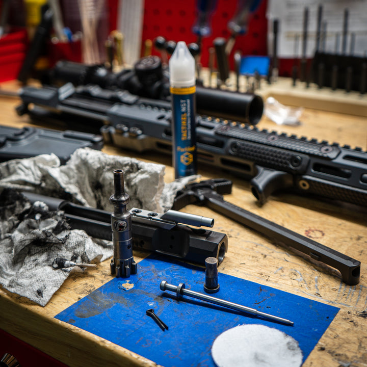 Tactikel NST on a gun cleaning workbench with firearm parts and maintenance tools